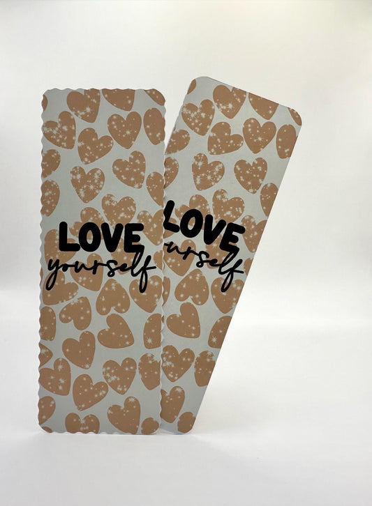 A wavy edges and straight edges bookmarks with a heart pattern and the text 'LOVE yourself' printed in blue and brown tones on a white background.