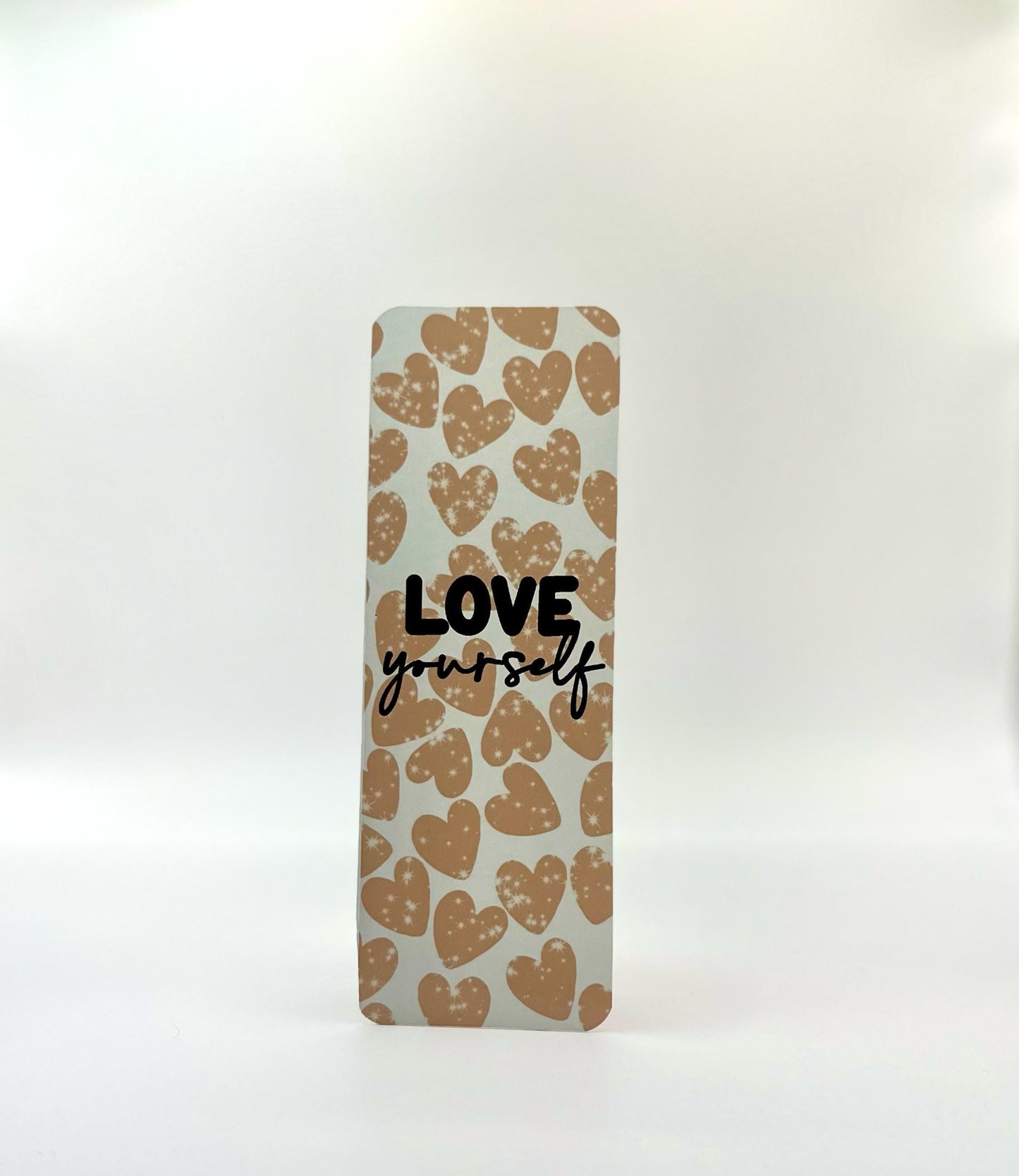 A straight edges bookmark with a heart pattern and the text 'LOVE yourself' printed in blue and brown tones on a white background.