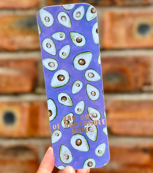 Avocado themed aethetic bookmark on purple background with golden text 'ran out of guacamole here'. Front detail