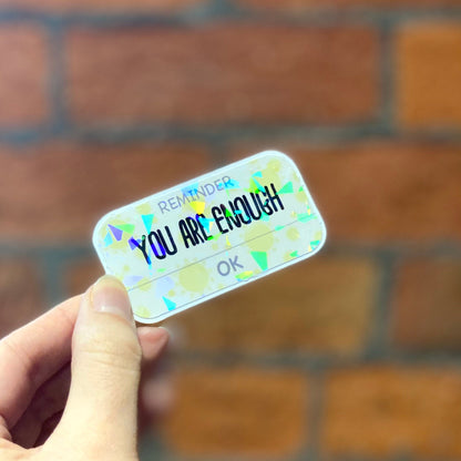Holographic aesthetic motivation sticker with text 'reminder you are enough'. Angle view
