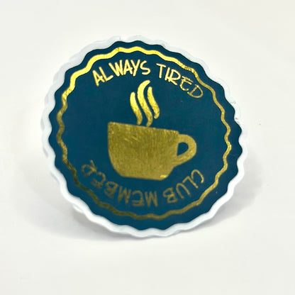 Aestetic sticker with a coffee cup design and text 'Always Tired Club Member' with gold details on white background. side View
UK small shop