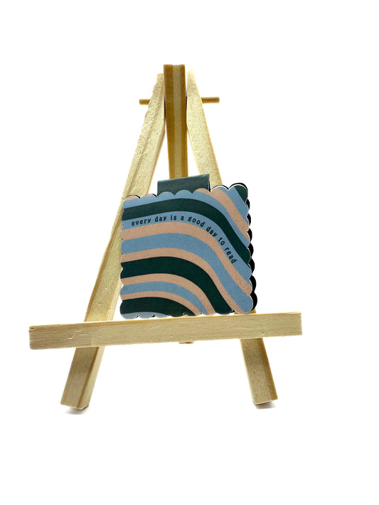Colorful magnetic bookmark with tex 'every day is a good day to read' on a wooden stand against a white background