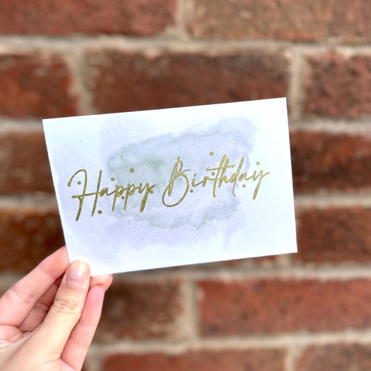 Aesthetic birthday card on watercolour background and gold detail text 'happy birthday'. Frontal detail