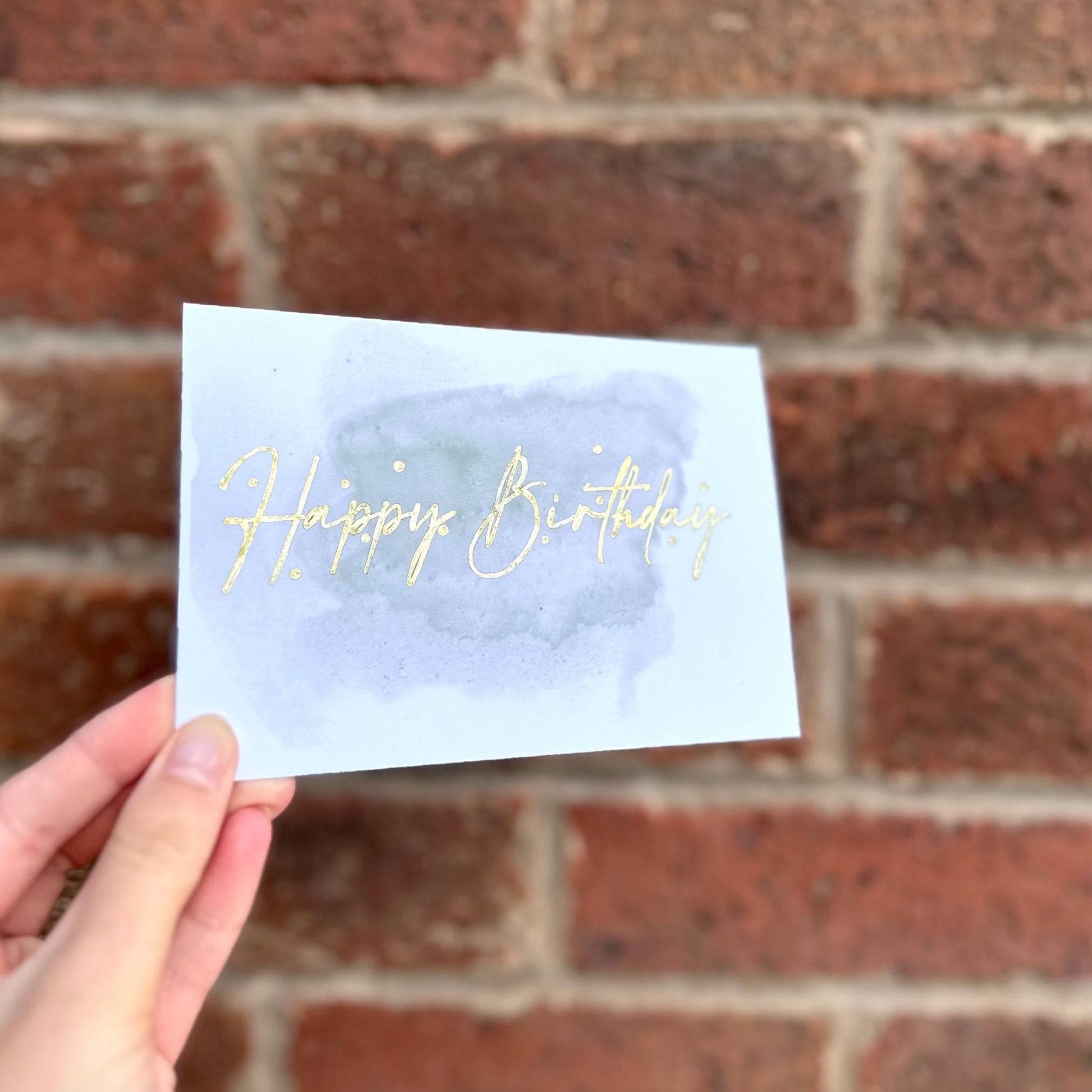 Aesthetic birthday card on watercolour background and gold detail text 'happy birthday'. Frontal 