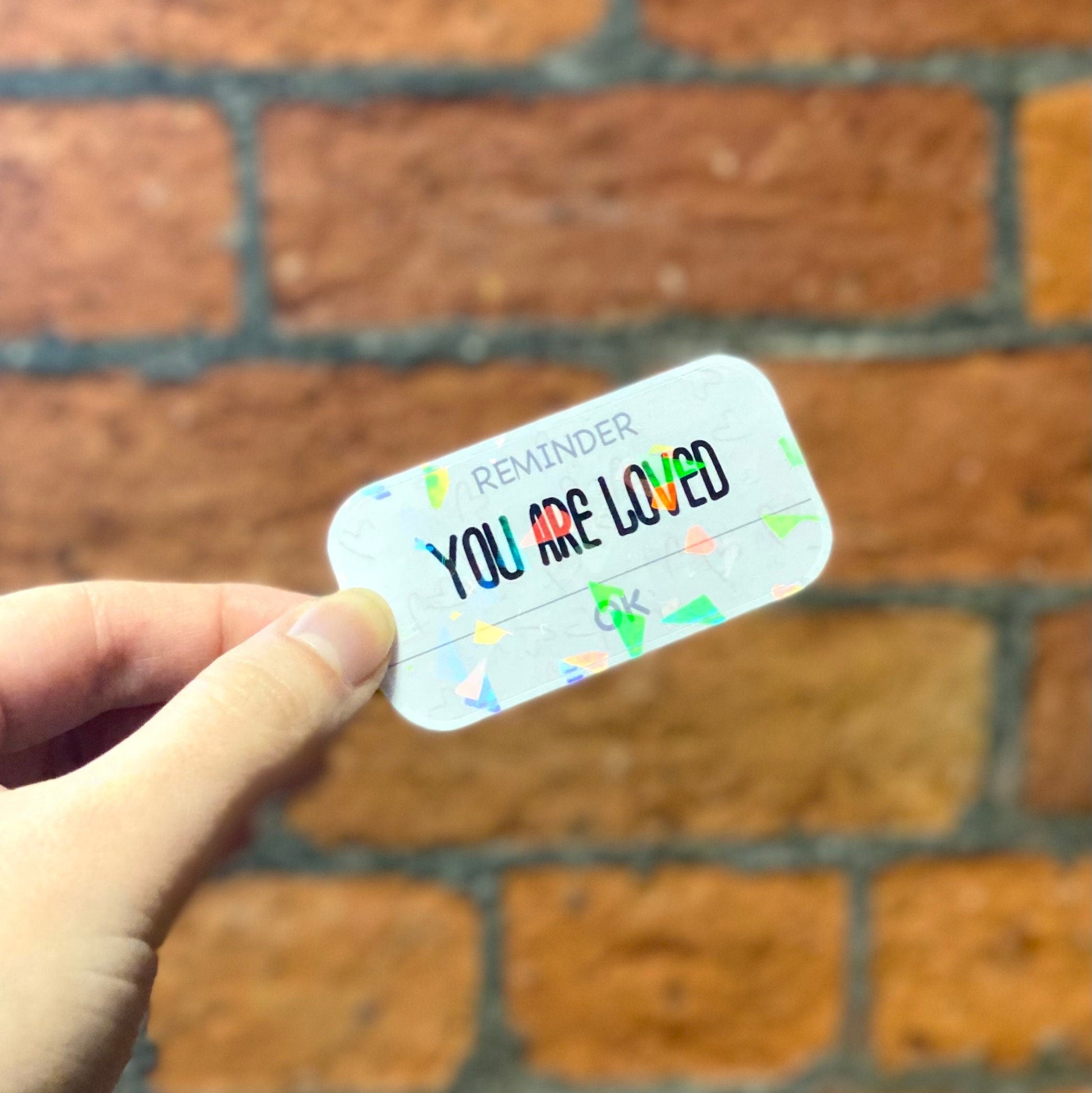 Holographic aesthetic sticker with the text 'YOU ARE LOVED'. Frontal