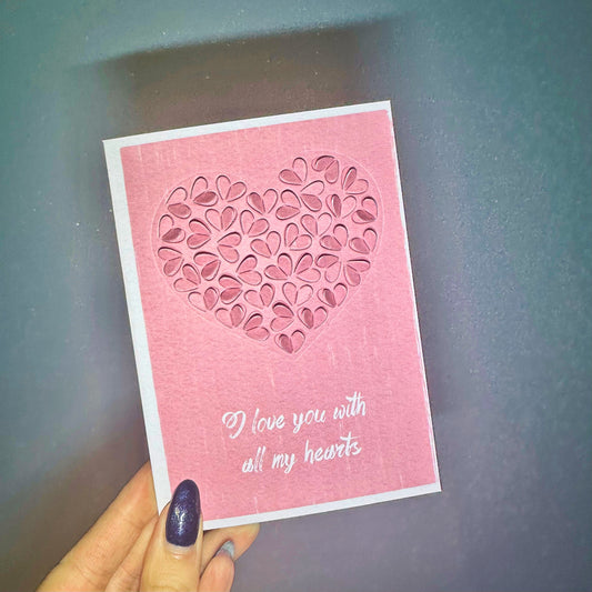 pink valentine card with cut out heats design agaings blue wall