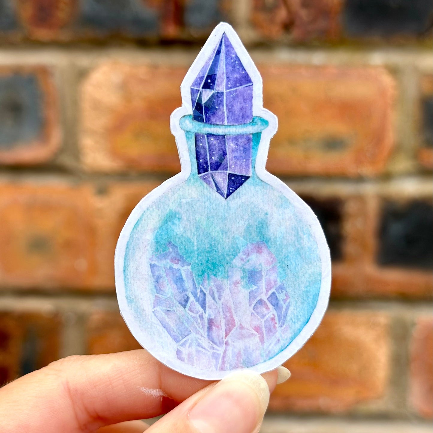 Sticker of a crystal in a potion bottle held against a brick wall. Frontal