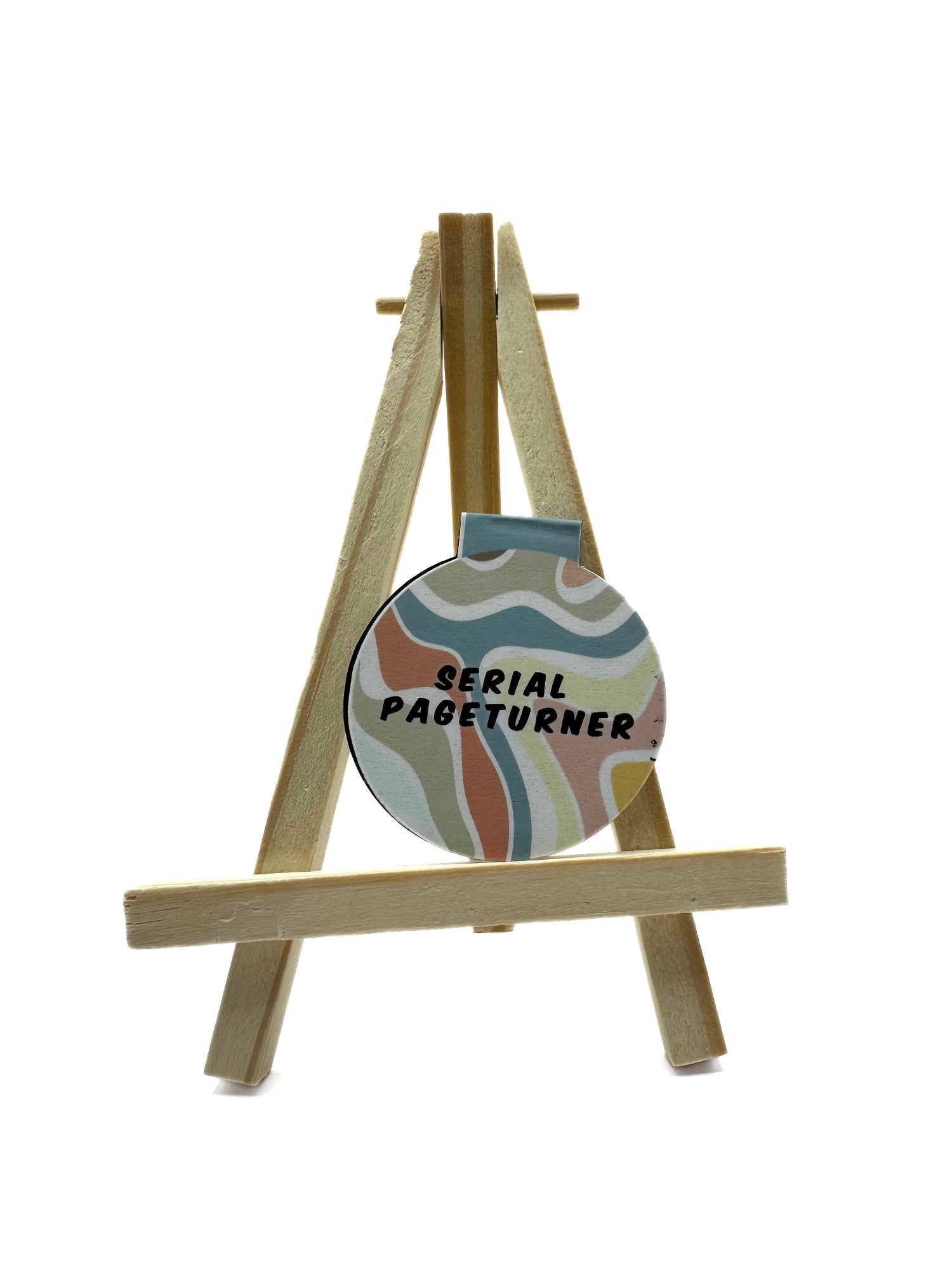 Round magnetic bookmark on a small easel with 'Serial Page Turner' text on colorfull groovy background.
