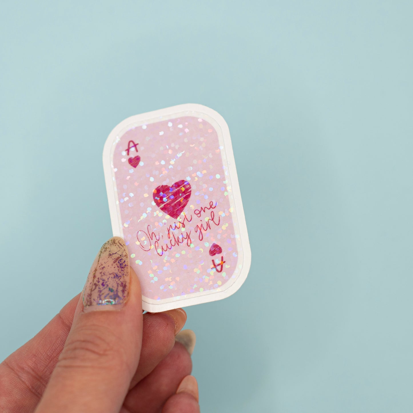  a small rectangular ace card sticker with rounded corners. The card has a light pink background with holographic dot overlay with a red heart, the letter A, and the phrase 'Oh my one lucky girl' in pink script.