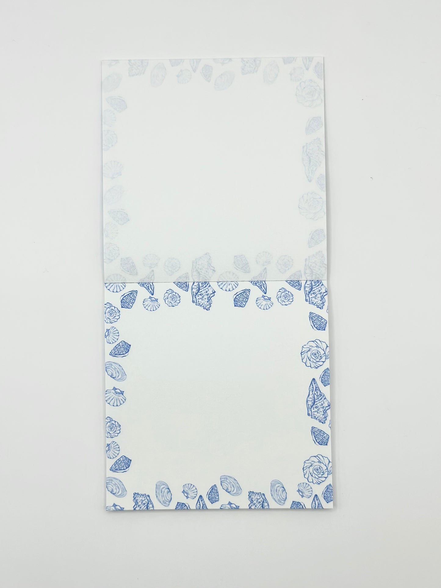 Square memo pad with a blue coastal border pattern, photographed flat against a plain white background.