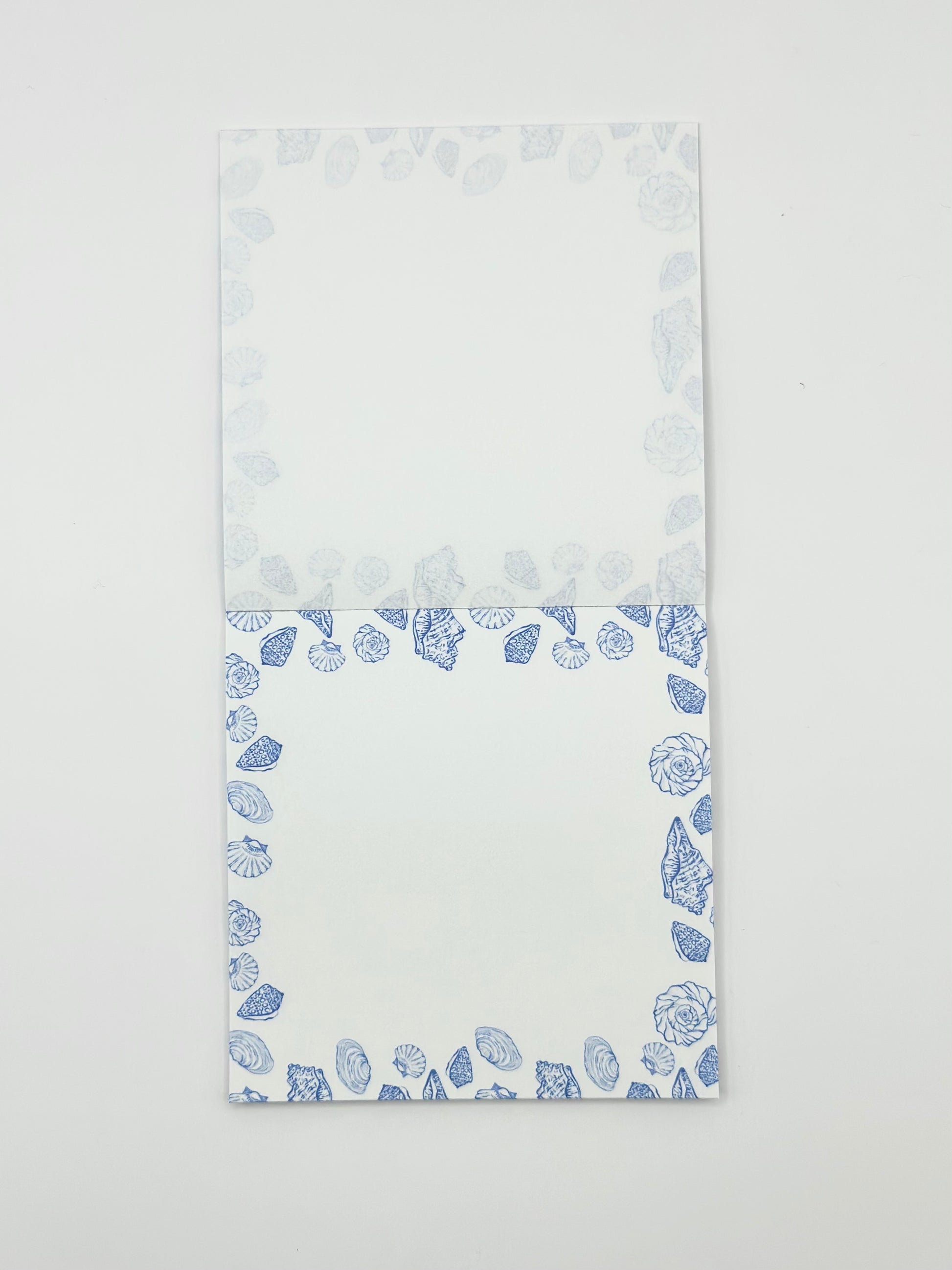 Square memo pad with a blue coastal border pattern, photographed flat against a plain white background.