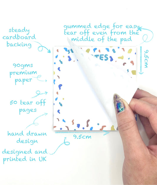 Hand holding a tear-off page of a square confetti themed memo pad with product features highlighted on a white background