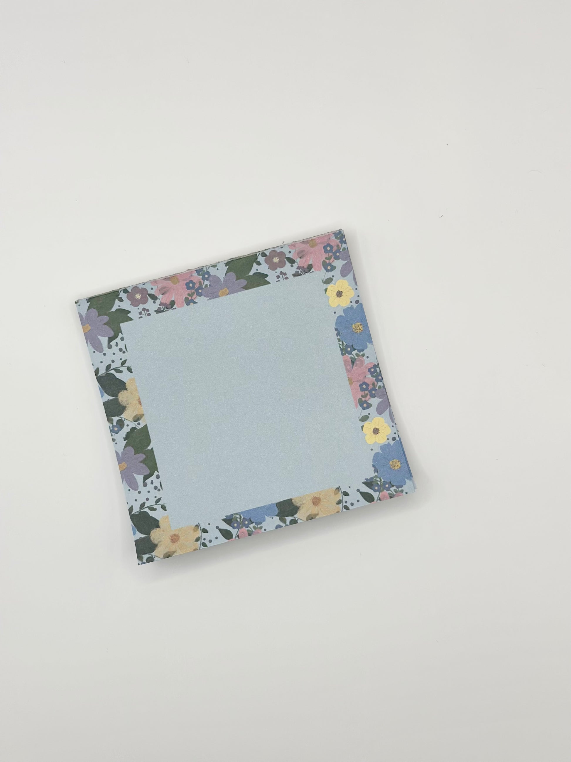 Floral-patterned square memo pad on a white background