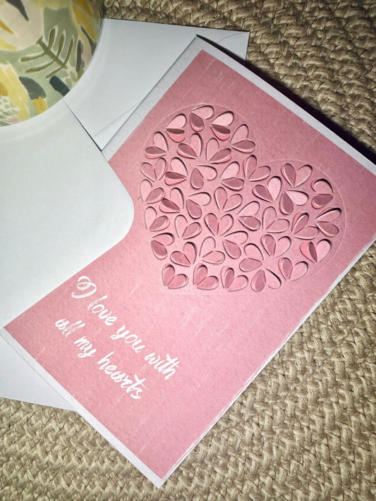 pink valentine day card with cut out hearth shapes and text - i love you with all my hearts on textured background 
