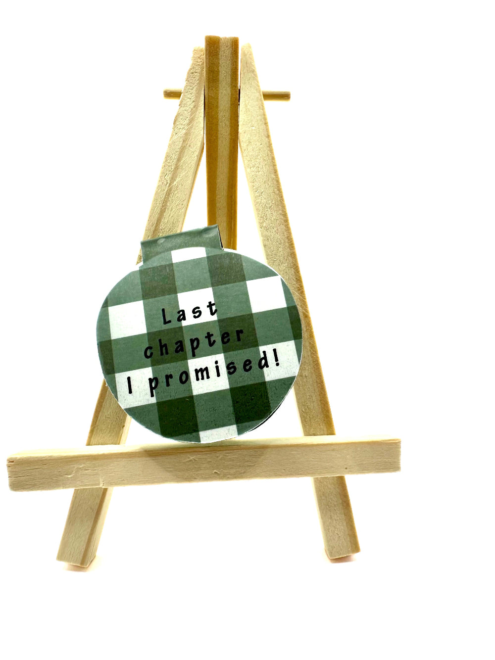 Green and white checkered magnetic bookmark with text 'last chapter i promised' on a wooden stand against a white background 