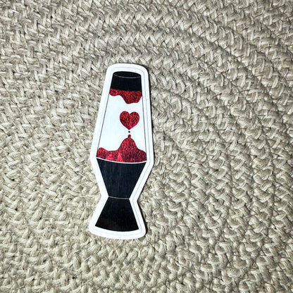 Sticker of a lava lamp with red lava and a heart on a textured beige surface