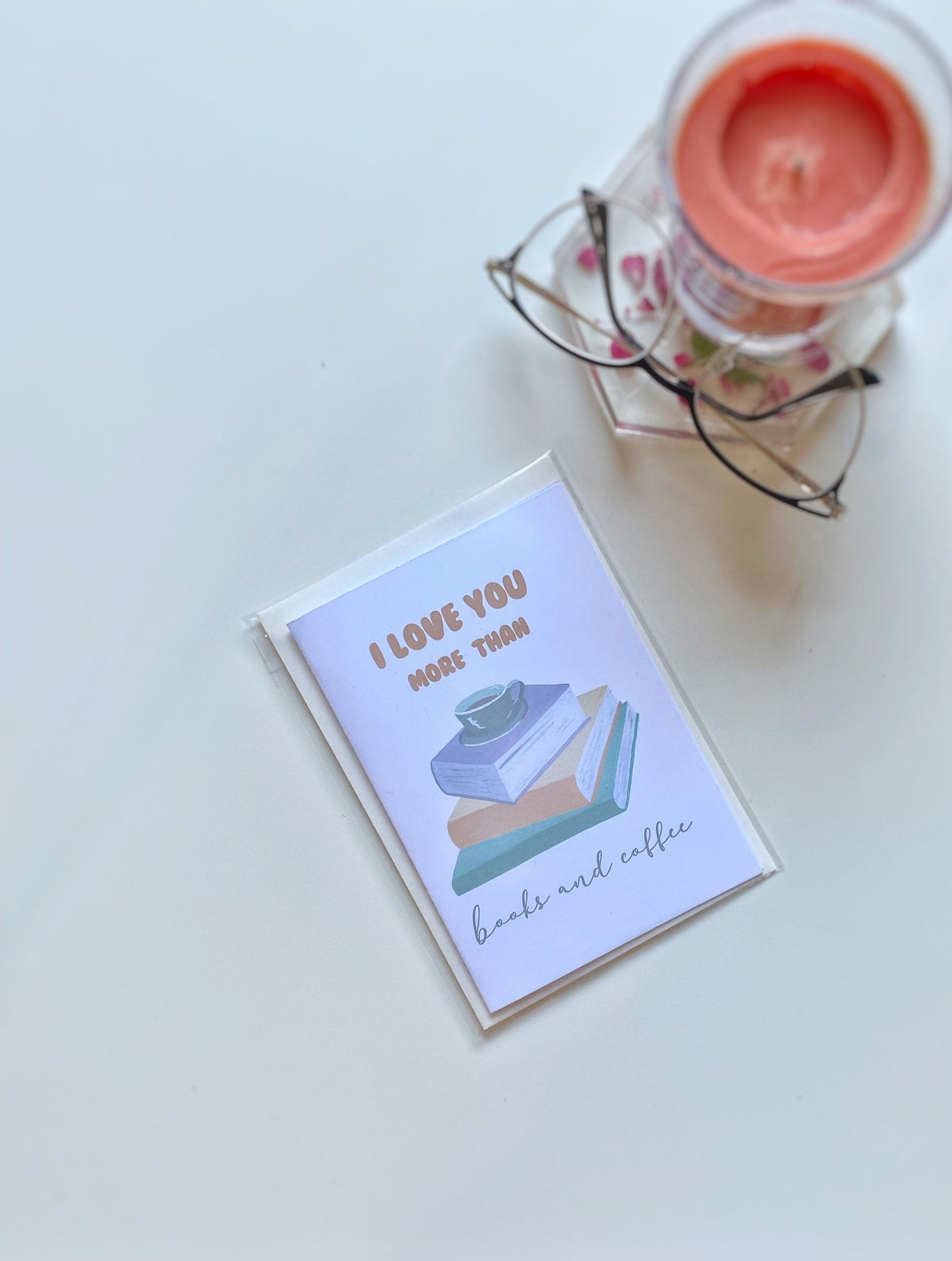 A greeting card with the text 'I LOVE YOU MORE THAN books and coffee' displayed with envelope