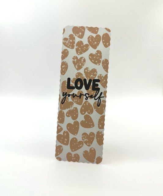 A wavy edges bookmark with a heart pattern and the text 'LOVE yourself' printed in blue and brown tones on a white background.