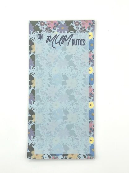 A vertical memo pad with a floral-patterned border and a light blue floral center. The top reads 'ON MUM DUTIES' in stylised lettering.