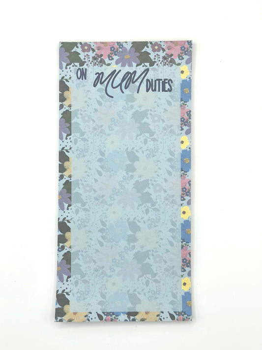 A vertical memo pad with a floral-patterned border and a light blue floral center. The top reads 'ON MUM DUTIES' in stylised lettering.