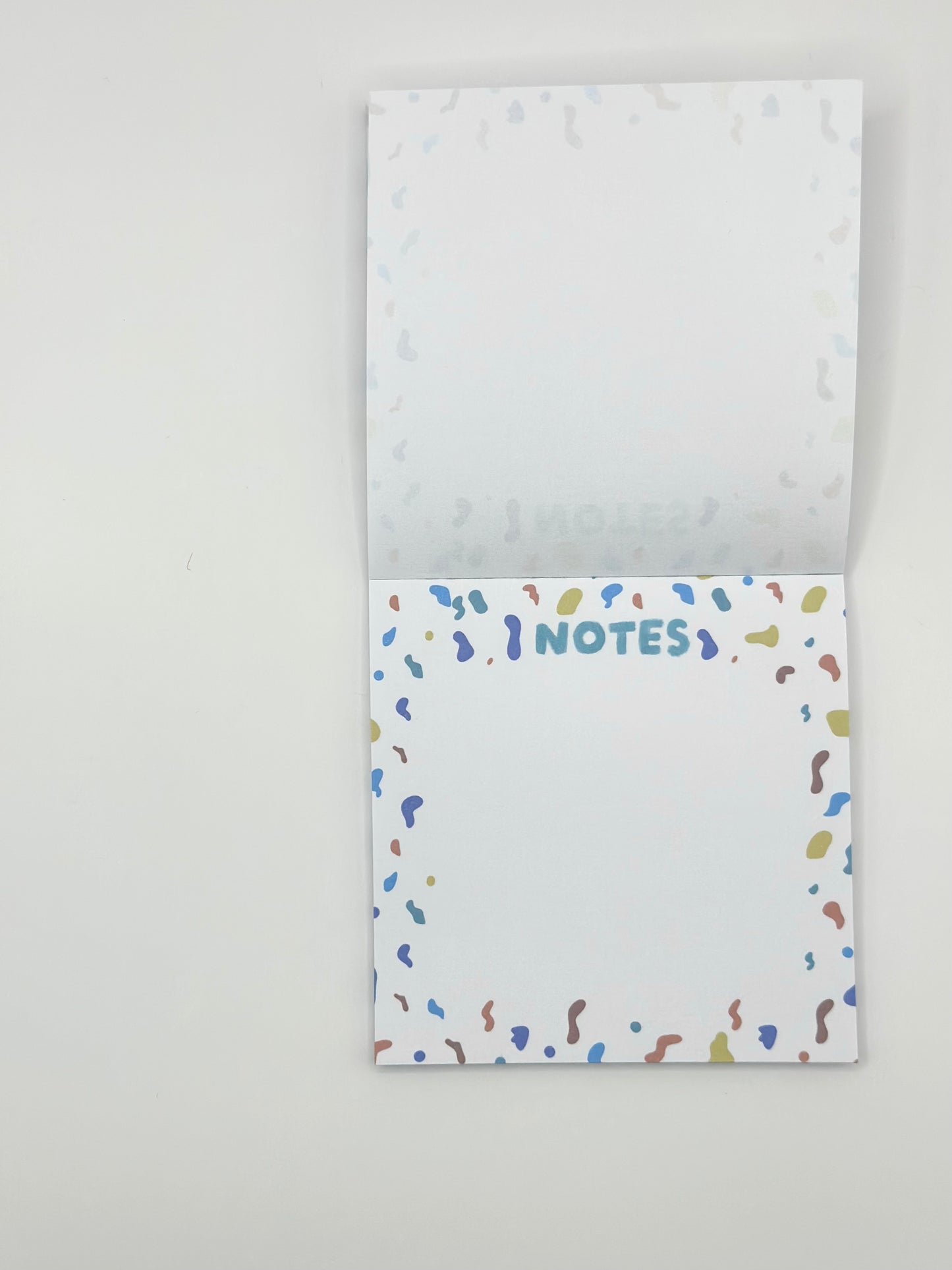 Square memo pad with colorful confetti design and 'Notes' text on a white background