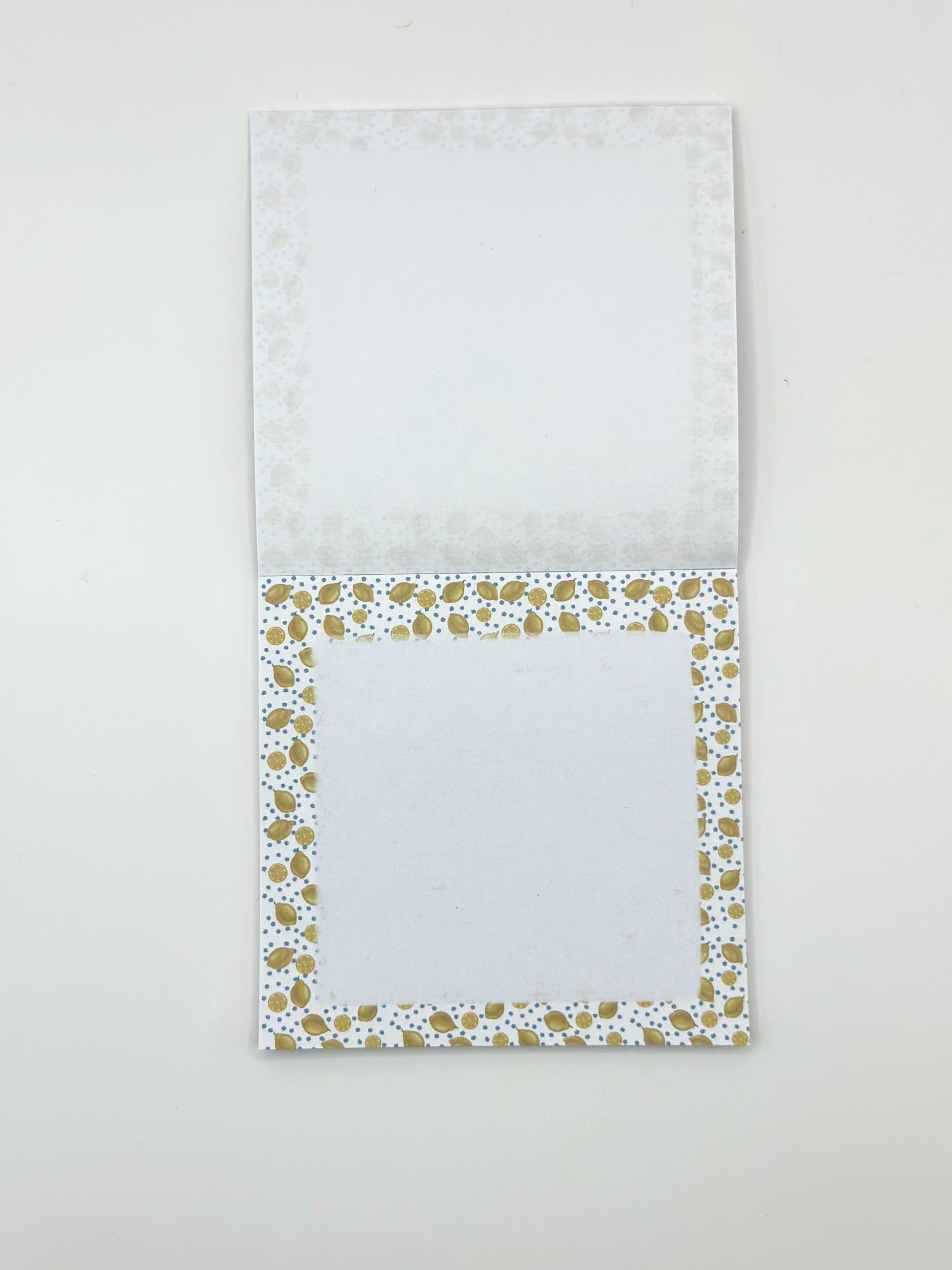 Open square memo pad with a lemon design border on a light white background
