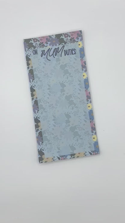 A vertical memo pad with a floral-patterned border and a light blue floral center. The top reads 'ON MUM DUTIES' in stylised lettering.