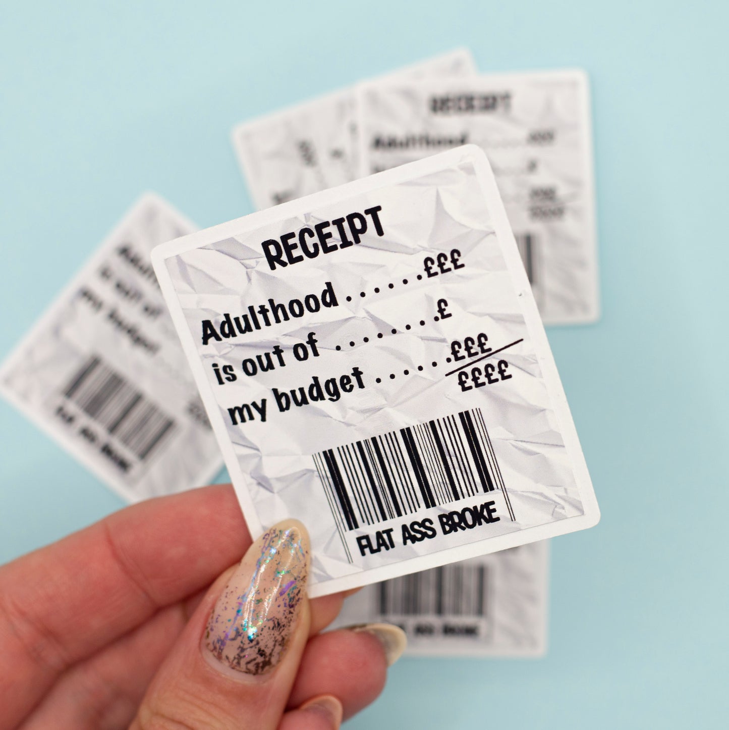 A crumpled white receipt-style sticker with black text reading 'RECEIPT Adulthood is out of my budget flat ass broke'.