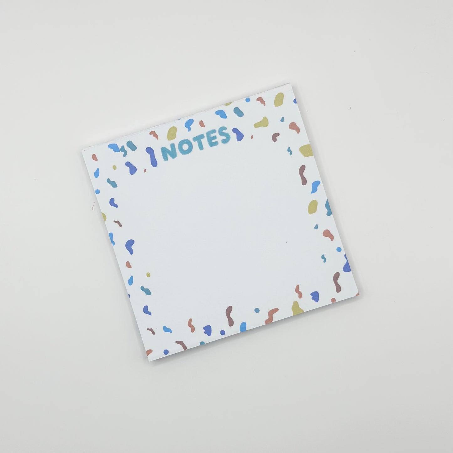 square memo pad with colorful text 'NOTES' and confetti border on a white  background