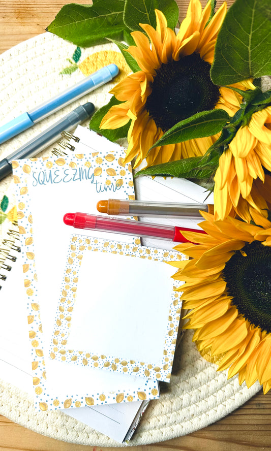 Sunflowers on a desk with lemon themed notepad and memo pad