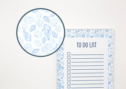 A white to-do list pad with a blue seashell pattern border, shown next to a circular close-up inset of the matching seashell pattern.